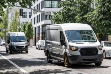 Zwei Transporter stehen in einer belebten Innenstadtstraße mit dichter Bebauung